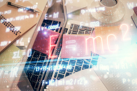 Physics and math theme hologram with formula drawings over computer on the desktop background. Top view. Multi exposure. Concept of education.の写真素材