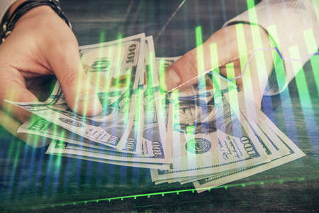 Multi exposure of financial graph drawing hologram and USA dollars bills and man hands. Analysis...