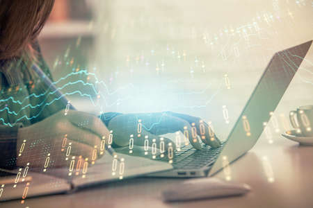 Double exposure of businesswoman hands typing on computer and forex graph hologram drawing....