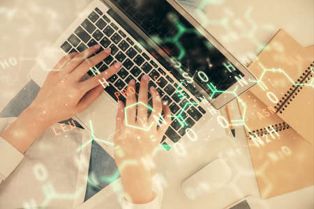 Double exposure of woman hands working on computer and formula hologram drawing. Top View. Science concept.の写真素材