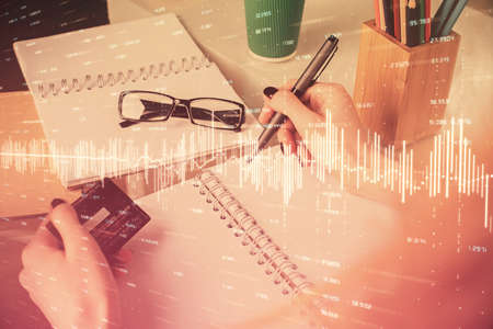 Multi exposure of woman on-line shopping holding a credit card and financial graph drawing. Stock...