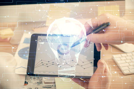 Double exposure of man's hands holding and using a digital device and bulb hologram drawing. Idea...