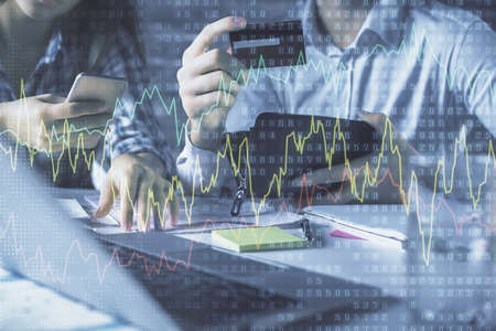 Double exposure of man and woman on-line shopping holding a credit card and forex graph hologram...