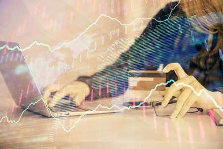 Double exposure of woman on-line shopping holding a credit card and financial graph drawing. Stock...
