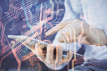 Double exposure of man's hands holding and using a digital device and tech theme hologram drawing....