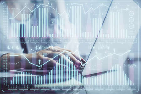 Double exposure of woman hands typing on computer and financial graph hologram drawing. Stock market...
