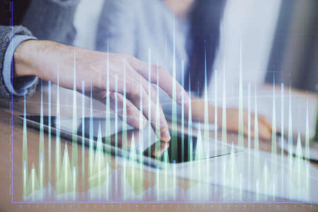 Double exposure of forex graph drawing and man and woman working together holding and using a mobile device. Trade concept.の写真素材