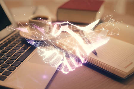 Double exposure of handshake drawing and desktop with coffee and items on table background. Concept of partnershipの写真素材