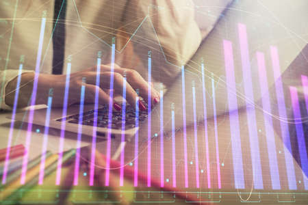 Double exposure of woman hands typing on computer and financial graph hologram drawing. Stock market...
