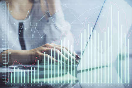 Double exposure of woman hands typing on computer and financial graph hologram drawing. Stock market...