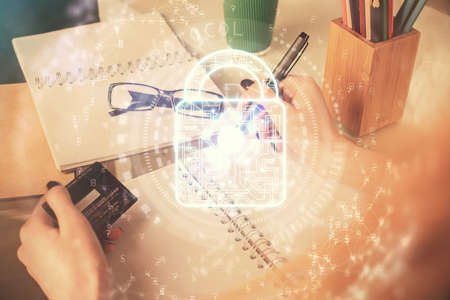 Double exposure of woman on-line shopping holding a credit card and Lock hologram drawing. Security...