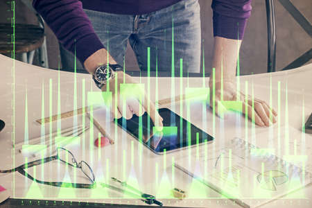 Double exposure of man's hands holding and using a digital device and forex graph drawing. Financial...
