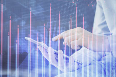 Double exposure of man's hands holding and using a digital device and forex graph drawing. Financial...