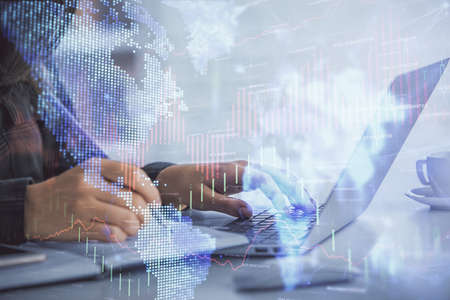 Double exposure of businesswoman hands typing on computer and forex graph hologram drawing....