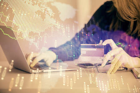 Double exposure of woman on-line shopping holding a credit card and financial graph drawing. Stock...