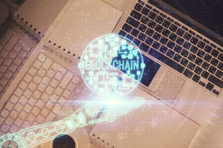 Blockchain theme hologram drawings over computer on the desktop background. Top view. Double...