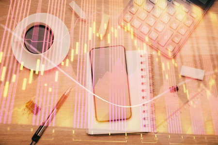Multi exposure of forex graph hologram over desktop with phone. Top view. Mobile trade platform...