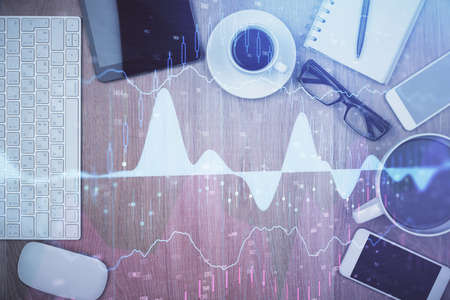 Double exposure of financial chart hologram over desktop with phone. Top view. Mobile trade platform concept.の写真素材