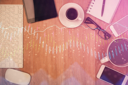 Double exposure of financial chart hologram over desktop with phone. Top view. Mobile trade platform concept.の写真素材
