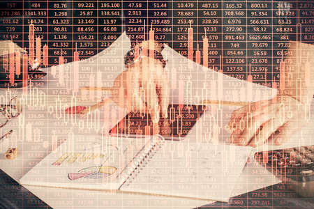 Double exposure of man's hands holding and using a digital device and forex graph drawing. Financial...