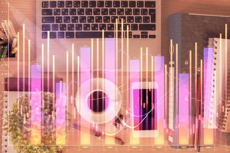 Double exposure of financial graph hologram over desktop with phone. Top view. Mobile trade platform concept.の写真素材