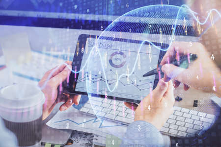 Double exposure of man's hands holding and using a phone and financial chart drawing. Market...