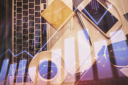 Double exposure of financial chart drawing over table background with computer. Concept of research...