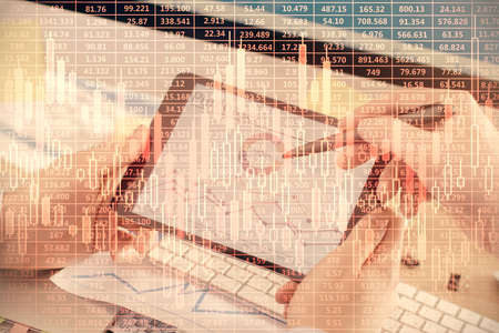 Double exposure of man's hands holding and using a phone and financial chart drawing. Market...