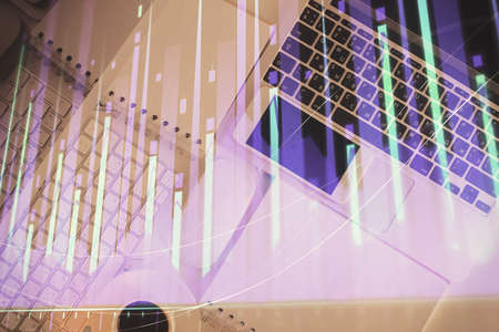 Financial market graph and top view computer on the desktop background. Multi exposure. Investment...