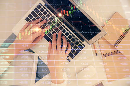 Double exposure of woman hands working on computer and forex graph hologram drawing. Top View....