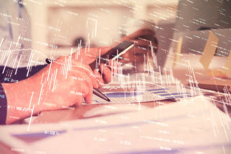 Double exposure of man's hands holding and using a phone and financial chart drawing. Market...