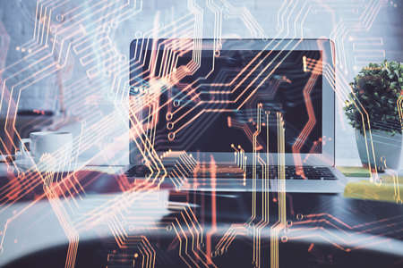 Computer on desktop in office with technology theme hologram. Double exposure. Tech concept.