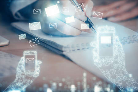E-mail envelop theme hologram over hands taking notes background. Concept of electronic mail. Double exposureの写真素材