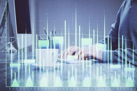 Multi exposure of graph with man typing on computer in office on background. Concept of hard work.