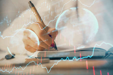 Multi exposure of woman's hands making notes with forex graph hologram. Concept stock market...