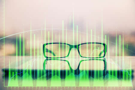 Financial graph hologram with glasses on the table background. Concept of business. Double exposure.