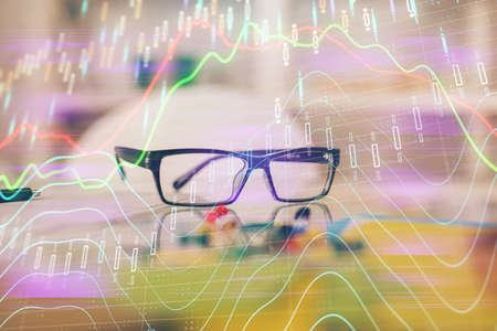 Financial chart hologram with glasses on the table background. Concept of business. Double exposure.