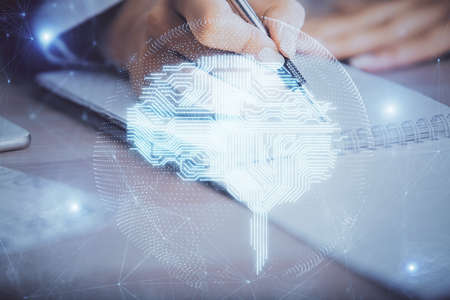 Double exposure of woman's writing hand on background with brain hud. Concept of learning.