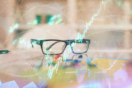 Financial chart hologram with glasses on the table background. Concept of business. Double exposure.の写真素材