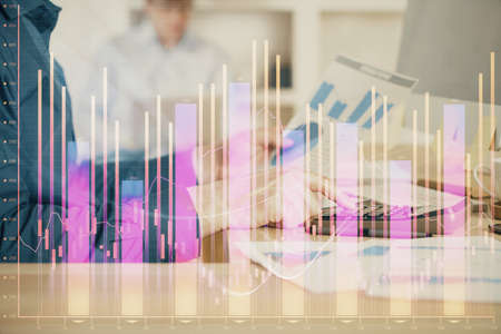 Double exposure of graph with man typing on computer in office on background. Concept of hard work. Closeup.の写真素材