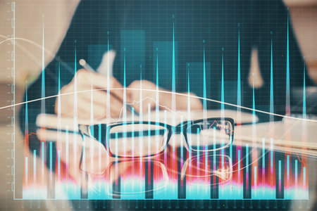 Forex chart hologram on hand taking notes background. Concept of analysis. Multi exposureの写真素材