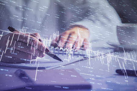 Double exposure of woman's hands making notes with forex graph hologram. Concept technical analysis.の写真素材
