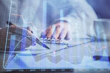 Double exposure of woman's hands making notes with forex graph hologram. Concept technical analysis.