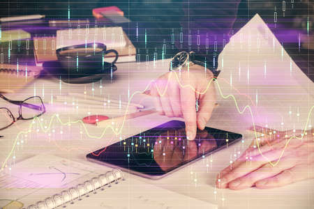 Double exposure of man's hands holding and using a digital device and forex graph drawing. Financial...