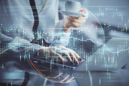 Double exposure of businesswoman hands typing on computer and financial graph hologram drawing....