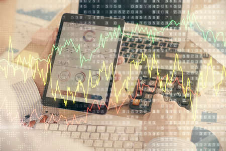 Double exposure of man's hands holding and using a digital device and forex graph drawing. Financial...