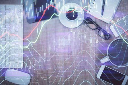 Double exposure of financial chart hologram over desktop with phone. Top view. Mobile trade platform...