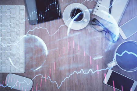 Double exposure of financial chart hologram over desktop with phone. Top view. Mobile trade platform...