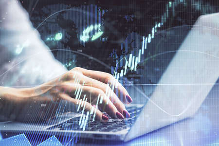 Double exposure of businesswoman hands typing on computer and forex chart hologram drawing....