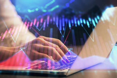 Double exposure of businesswoman hands typing on computer and forex chart hologram drawing....